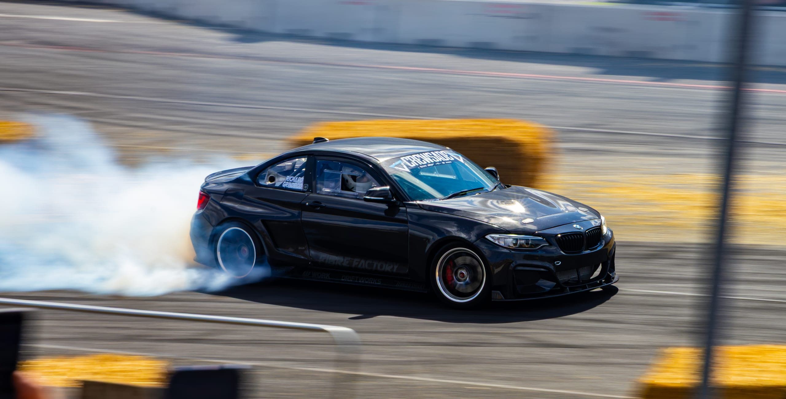 A dark coupe trailing a long line of tyre smoke, Gravity 2026
