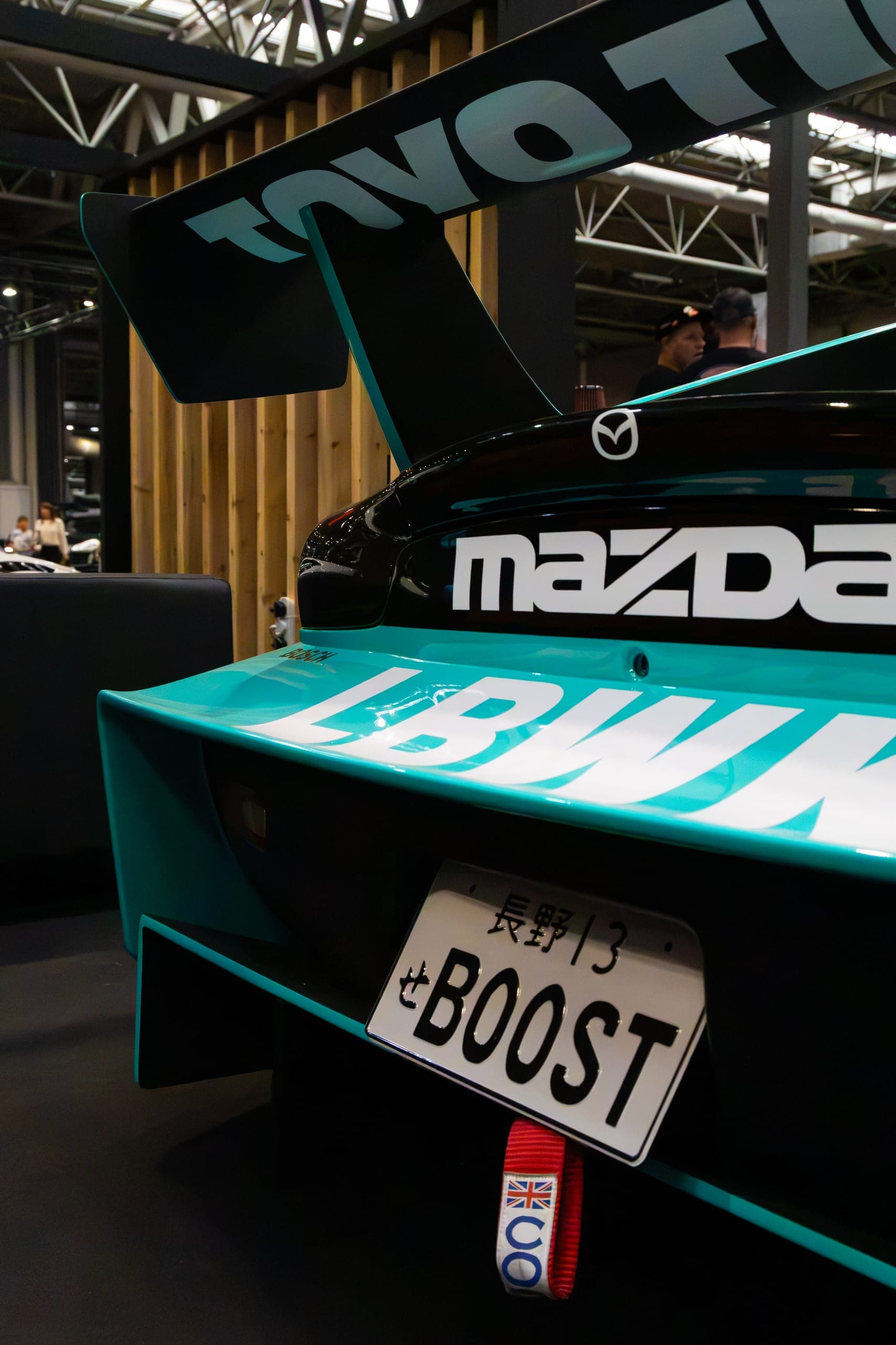 A rear wing and badge on a teal widebody, Gravity 2026